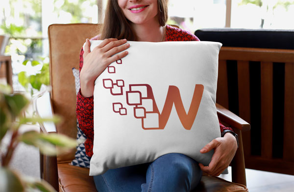 Wallario Logo Mockup. Logo auf einem Kissen platziert, das von einer Frau gehalten wird. Die Frau sitzt in einem Lederstuhl und lächelt.